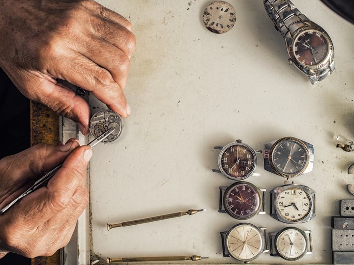 Orologiai Orologiaio ripara vecchi orologi con attrezzi su banco da lavoro