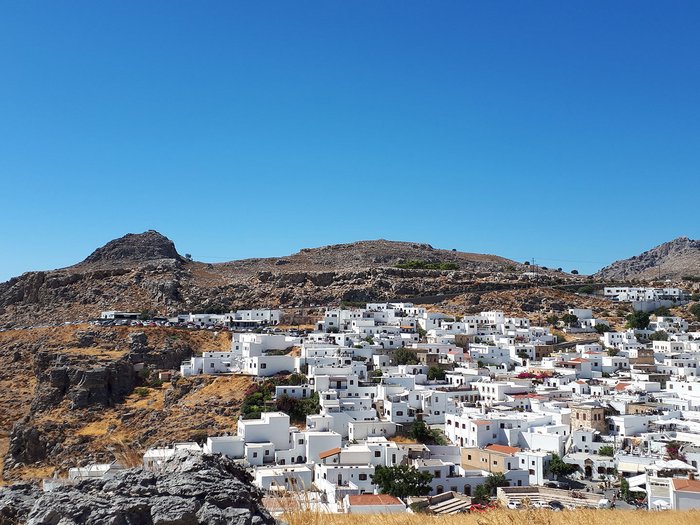 Althandwerker Rhodos 2022 © lvh.apa Blick auf weiß gestrichene Häuser vor felsigem, bergigem Gelände unter klarem blauen Himmel