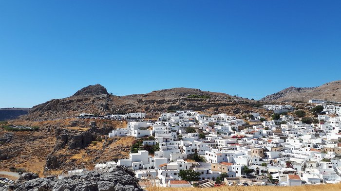 Althandwerker Rhodos 2022 © lvh.apa Blick auf weiß gestrichene Häuser vor felsigem, bergigem Gelände unter klarem blauen Himmel