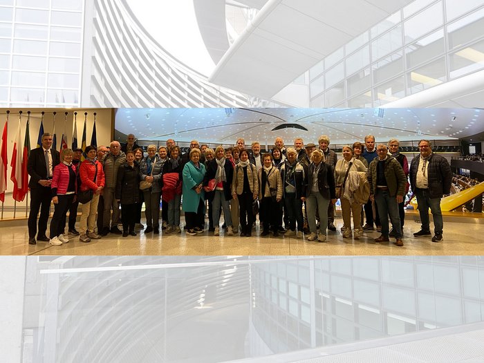 Althandwerker/innen im Herzen der Europäischen Union Gruppenfoto von Erwachsenen vor einem Raum mit mehreren Länderflaggen