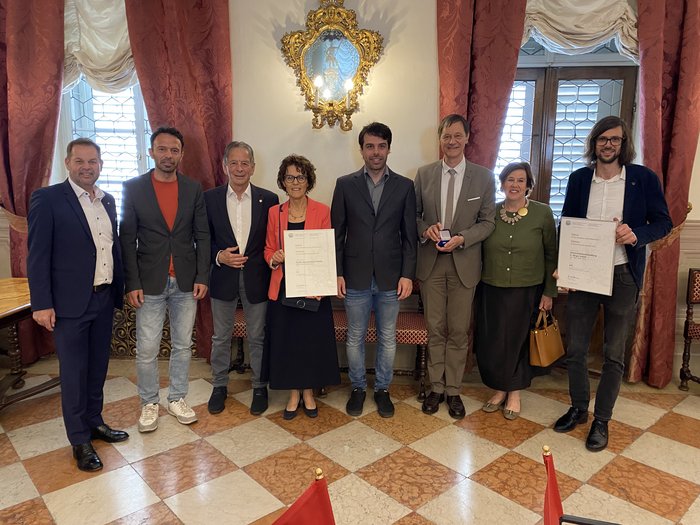Consegna del premio Economia Alto Adige 2025 Nove persone in ambiente elegante con diplomi e medaglia in mano