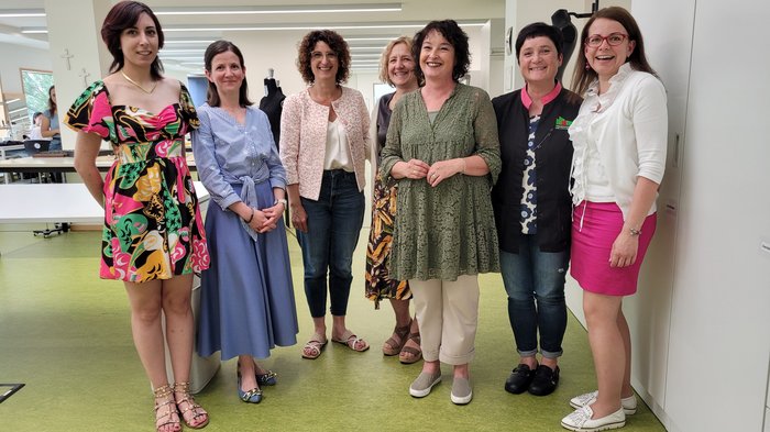 Praktischer Austausch Sieben Frauen in einem hellen Raum stehen nebeneinander und lächeln