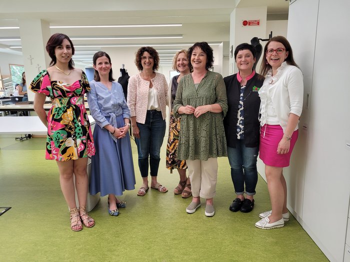 Praktischer Austausch Sieben Frauen in einem hellen Raum stehen nebeneinander und lächeln