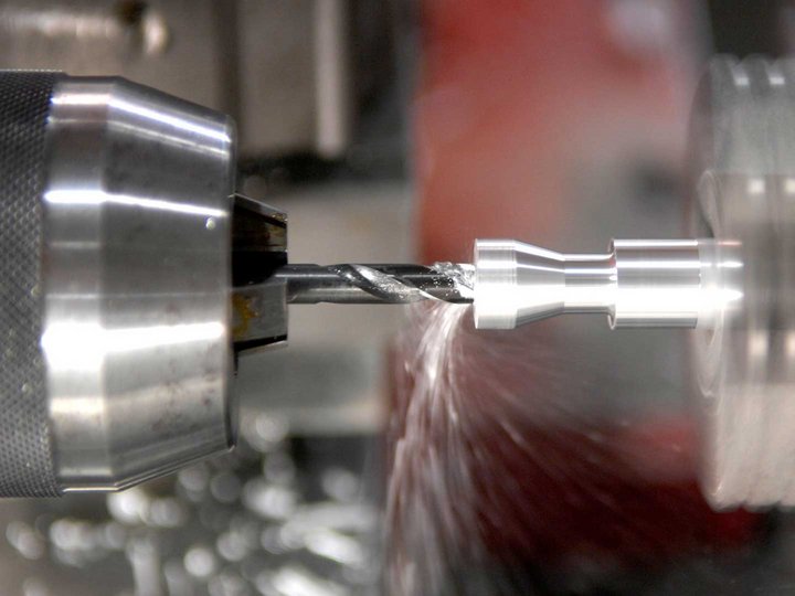 Congegnatori meccanici e attrezzisti Tornio che lavora un pezzo di metallo con trapano in movimento