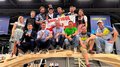 WorldSkills 2022 Special Edition: Zimmerer Marcel Bolego holt Silbermedaille Gruppenfoto von Personen auf einer Holzkonstruktion mit Südtirol-Flagge bei Zimmermannswettbewerb