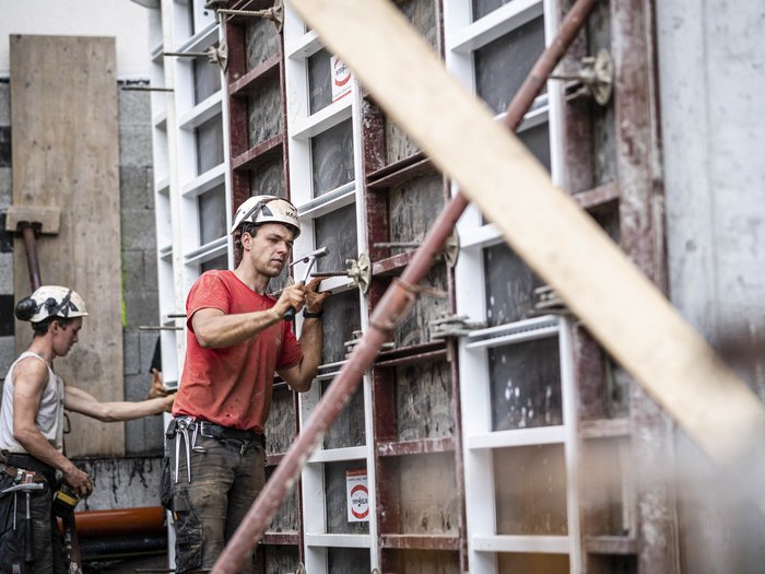 Le ore di lavoro in cantiere Operaio con casco lavora alla casseratura in cantiere edile