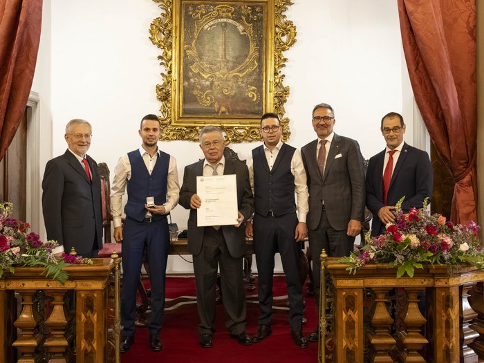 Premio Economia 2026: premiate 8 aziende associate lvh.apa Sei uomini in abiti formali durante una cerimonia di consegna del certificato davanti a un quadro decorativo
