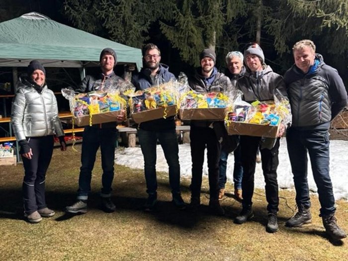 Lattlschießen der Handwerker/innen erfreut sich größter Beliebtheit Gruppe von sieben Personen mit Geschenkpaketen im Freien bei Nacht