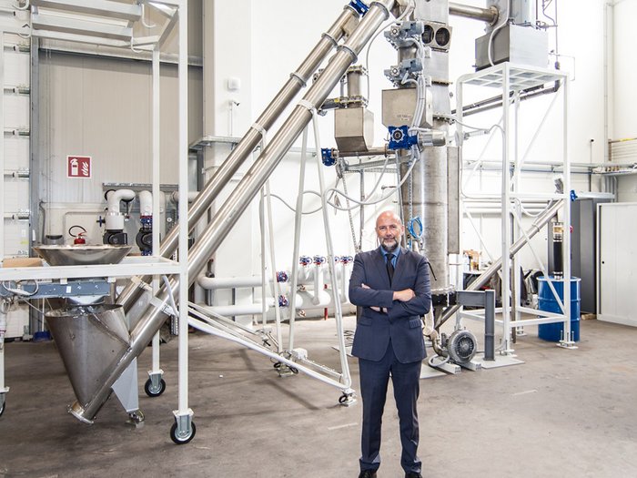 Neue Hightech-Anlage zur Vergasung von Biomasse im NOI Techpark Geschäftsmann steht vor komplexer Industrieanlage in Fabrikhalle