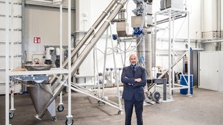 News Geschäftsmann steht vor komplexer Industrieanlage in Fabrikhalle