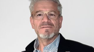 News Mann mit grauen Haaren, Holzbrille und gemustertem Hemd vor weißem Hintergrund