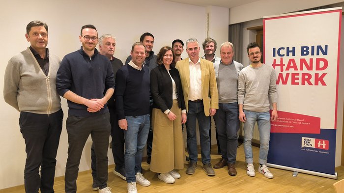 Metzgerhandwerk im Dialog: Ausbildung, Schlachthöfe und Zukunftsperspektiven Gruppe von elf Personen posiert vor Banner mit Text Ich bin Handwerk