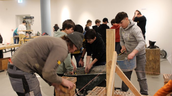 Una settimana intorno all‘artigianato Bambini partecipano a un laboratorio di muratura con mattoni e malta