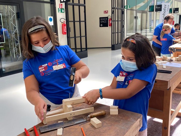Neue Auflage der Kids-Akademie 2022 Zwei Kinder mit Masken bearbeiten Holz am Werkbank in einem Makerspace