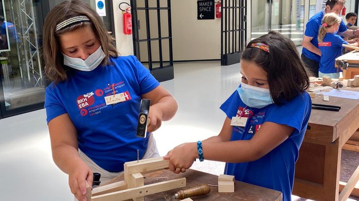 Neue Auflage der Kids-Akademie 2022 Zwei Kinder mit Masken bearbeiten Holz am Werkbank in einem Makerspace