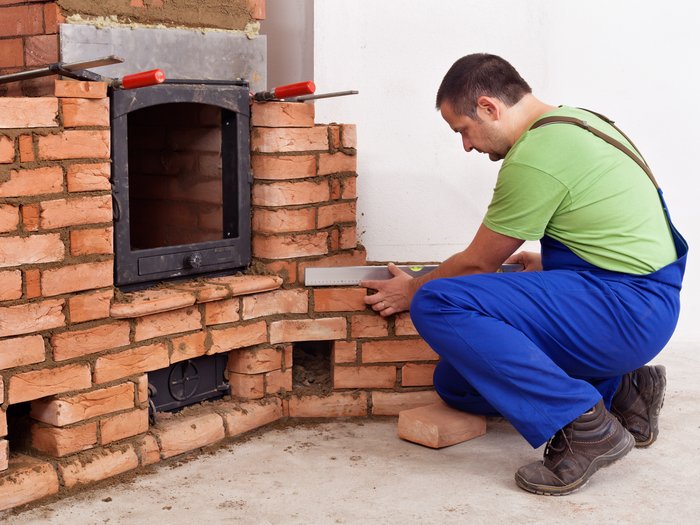 K.O. durch CO - Überprüfung bringt Sicherheit und wohlige Wärme Handwerker misst Mauerwerkskamin mit Wasserwaage