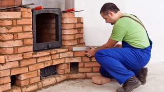 News Handwerker misst Mauerwerkskamin mit Wasserwaage