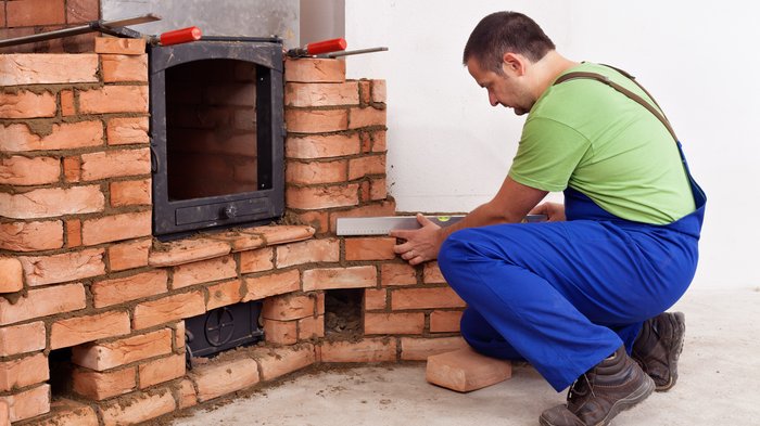 K.O. durch CO - Überprüfung bringt Sicherheit und wohlige Wärme Handwerker misst Mauerwerkskamin mit Wasserwaage