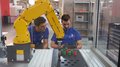 WorldSkills Italy: Obiettivo Lione Due uomini controllano un braccio robotico giallo in un'officina