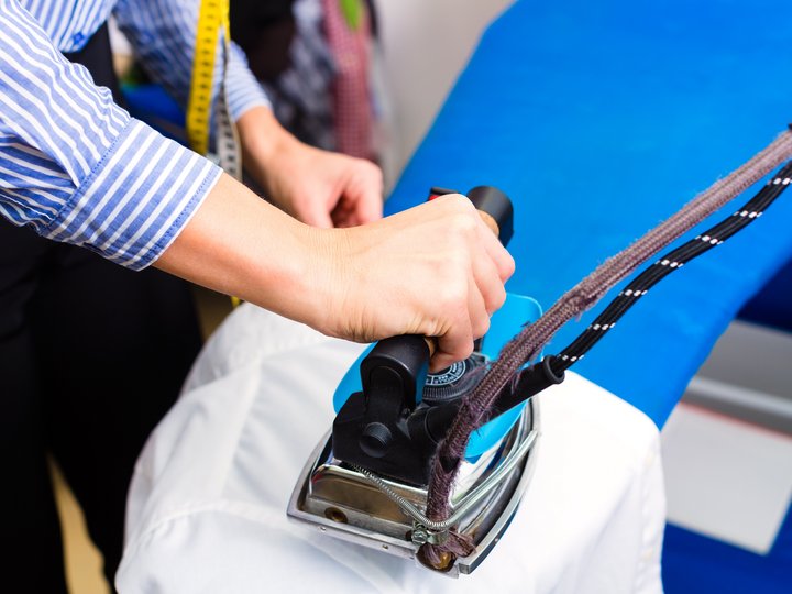 Pulitintori Persona che stira una camicia con un ferro da stiro professionale