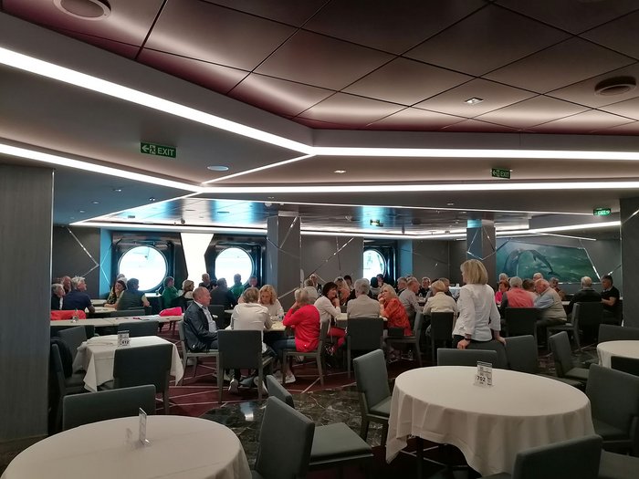 Artigiani anziani in crociera Gruppo di persone anziane sedute in una sala da pranzo moderna con finestre rotonde