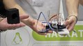 © lvh.apa Person hält elektronische Schaltung mit Kabeln und kleinem Lautsprecher vor Hackathon-Plakat