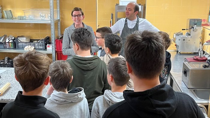 Mittelschule Innichen: Berufe praxisnah erleben Gruppe von Jungen lernt in einer Küche von einer Frau und einem Koch