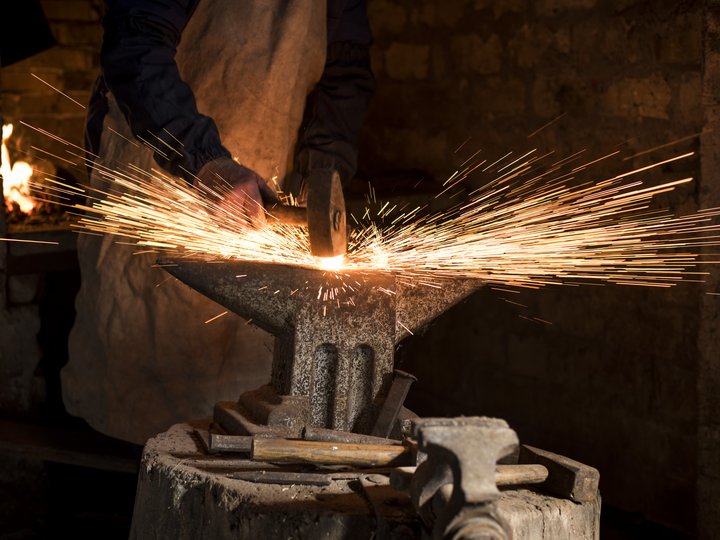 Schmiede und Schlosser Schmied arbeitet am Amboss, Funken fliegen beim Hammerschlag