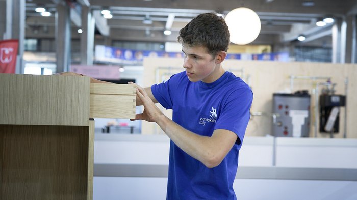 Textil-Event Junger Mann arbeitet an einem Holzschrank in einer Werkstatt