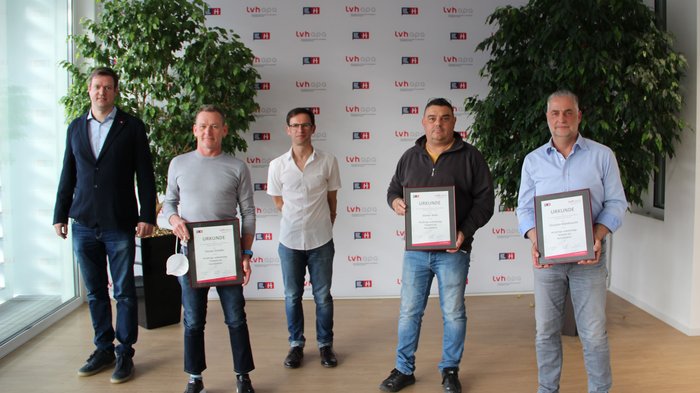 Gli spazzacamini formano una rete forte Cinque uomini in piedi davanti a una parete con logo LVH, tre tengono certificati in mano