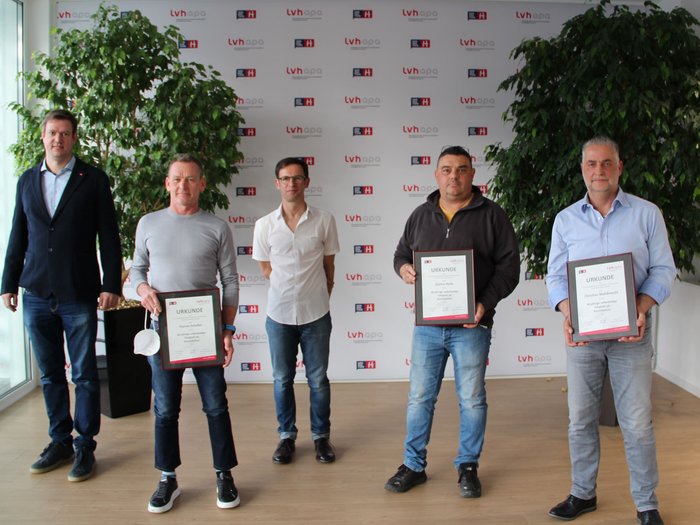 Gli spazzacamini formano una rete forte Cinque uomini in piedi davanti a una parete con logo LVH, tre tengono certificati in mano