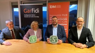 News Vier Personen sitzen am Tisch mit Zertifikaten vor Garfidi und IDM Bannern