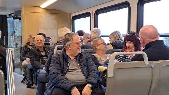 Viaggio autunnale degli artigiani anziani di lvh.apa: puro divertimento e panorama svizzero Diverse persone anziane sedute e conversano in una carrozza del treno.