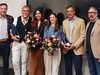 Home Sechs Personen stehen zusammen bei einer Feier, zwei halten Blumen und drei Geschenke
