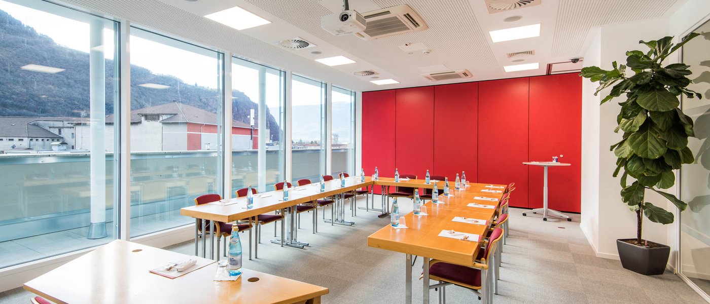 Vermietung Seminarräume Heller Konferenzraum mit U-förmigen Tischen, roten Stühlen und großen Fenstern