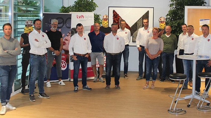 Die Helden der Baustelle: Nachwuchs-Handwerker gesucht! Gruppe von 14 Personen steht in einem Büro mit Bannern im Hintergrund