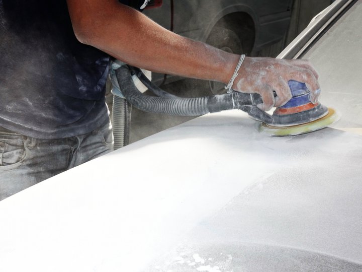 Karosserietechniker Hand schleift Autoteil mit elektrischem Schleifgerät