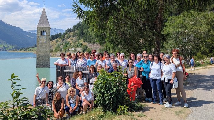 Öffentliche Aufträge: Bewusstsein für Mehrwerte Große Gruppe von Menschen vor versunkenem Kirchturm im See bei sonnigem Wetter