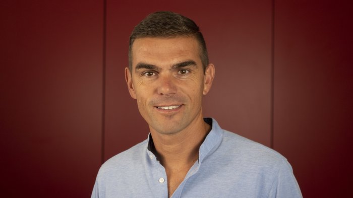 Neue Führung der Handwerker/innen in St. Pankraz Porträt eines lächelnden Mannes vor rotem Hintergrund