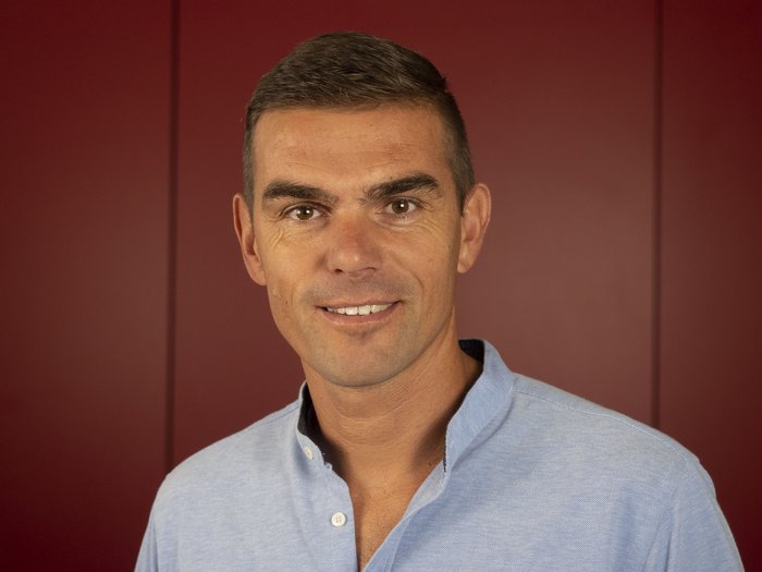 Neue Führung der Handwerker/innen in St. Pankraz Porträt eines lächelnden Mannes vor rotem Hintergrund