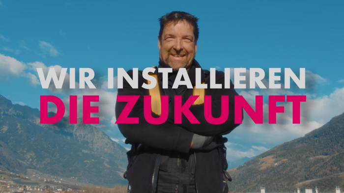 „Klimaschutz ist Arbeit und wir erledigen sie jeden Tag“ Lächelnder Mann vor Berglandschaft mit Text Wir installieren die Zukunft