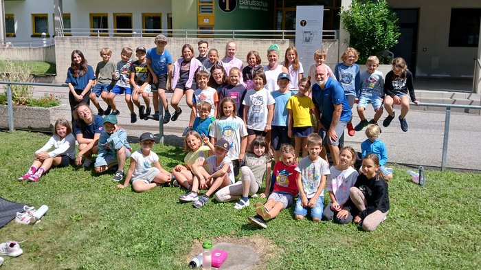 Mit Faden, Fantasie und Fingerfertigkeit – Die KidsAcademy in Brixen macht Handwerk erlebbar Gruppenfoto von Kindern und einem Erwachsenen vor einer Berufsschule im Sonnenschein
