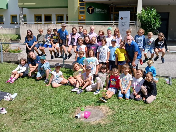 Creatività a misura di bambino: a Bressanone l’artigianato prende vita con la Kids Academy Foto di gruppo di bambini e un adulto davanti a una scuola professionale al sole