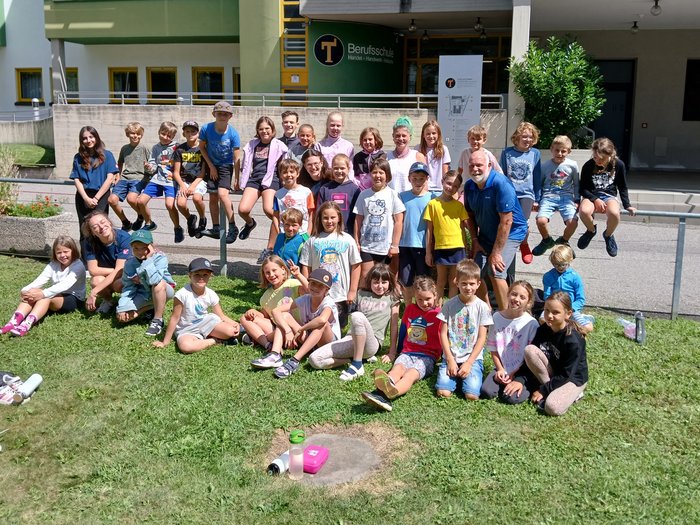 Mit Faden, Fantasie und Fingerfertigkeit – Die KidsAcademy in Brixen macht Handwerk erlebbar Gruppenfoto von Kindern und einem Erwachsenen vor einer Berufsschule im Sonnenschein