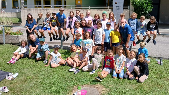 Creatività a misura di bambino: a Bressanone l’artigianato prende vita con la Kids Academy Foto di gruppo di bambini e un adulto davanti a una scuola professionale al sole