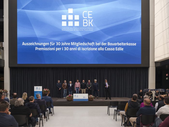 Bauarbeiterkasse der Autonomen Provinz Bozen: Ehrung der Mitglieder „30 Jahre Vertrauen“ Auszeichnung für 30 Jahre Mitgliedschaft bei Bauarbeiterkasse auf Bühne mit Publikum