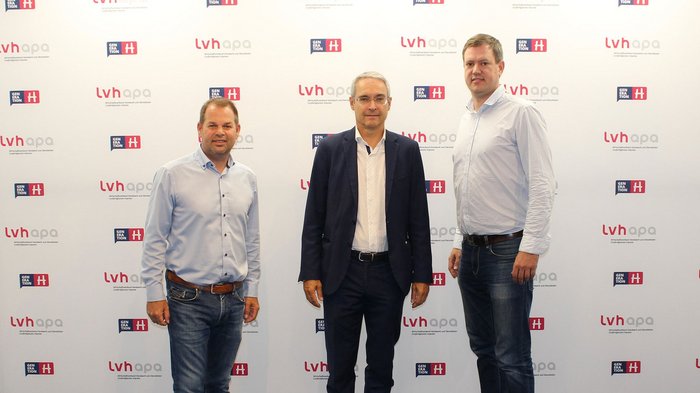 © lvh.apa Drei Männer stehen vor einer Wand mit lvhapa und Generation H Logos