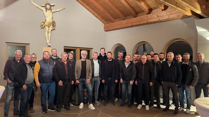 Fritz Ploner nuovo presidente del gruppo edilizia di lvh.apa Foto di gruppo di uomini in una stanza con travi in legno e crocifisso al muro