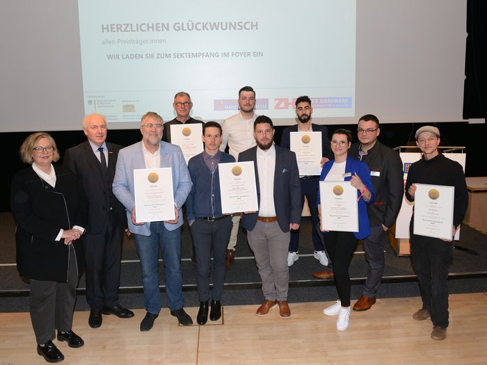 Zwei Südtiroler Unternehmen mit Bayrischem Staatspreis ausgezeichnet Gruppe von Personen mit Urkunden bei einer Preisverleihung vor Leinwand