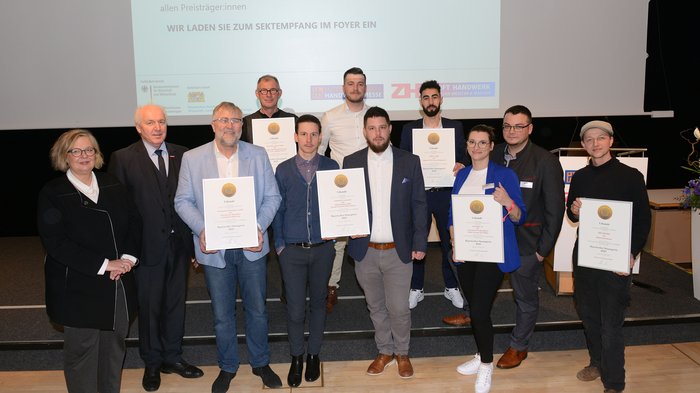 Zwei Südtiroler Unternehmen mit Bayrischem Staatspreis ausgezeichnet Gruppe von Personen mit Urkunden bei einer Preisverleihung vor Leinwand